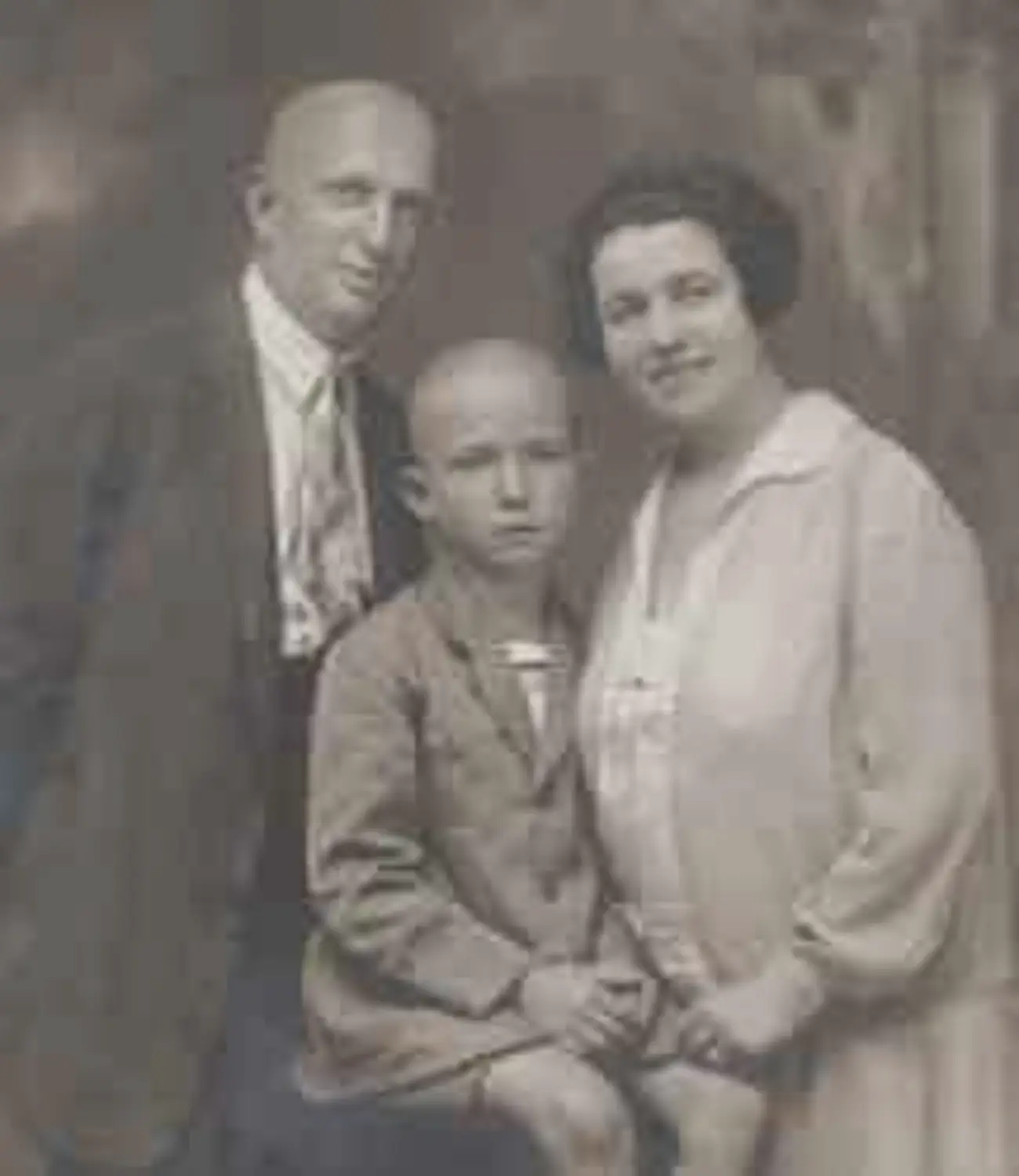 A 1920s family portrait as a low-resolution scan — soft, faded and marked by compression
